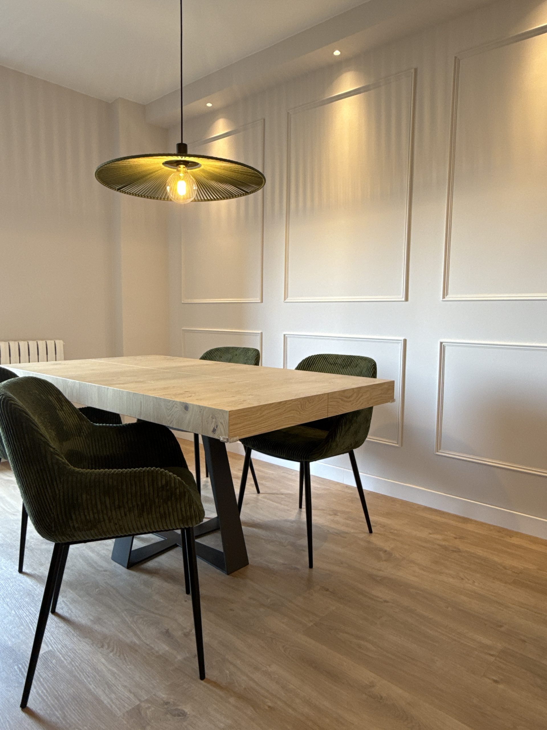 Mesa en roble nórdico con lámpara en cuerda verde alga y pared moldurada